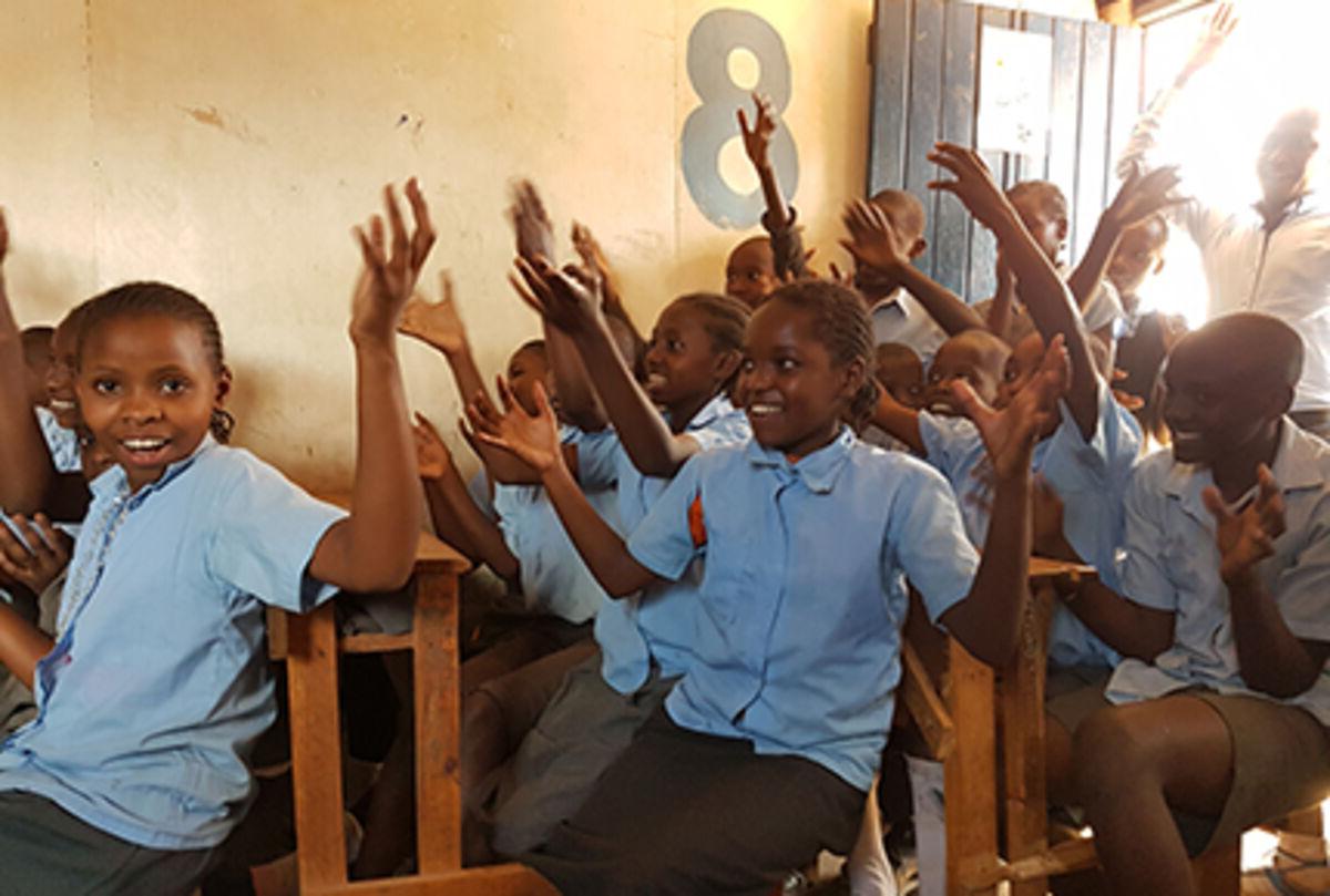 Classroom full with school children cheering in Kenya
